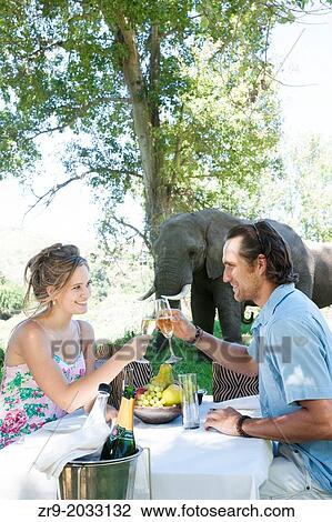 Caucasian couple enjoying a picnic outdoors near elephants, Botlierskop Game Reserve, Mosselbay, South Africa. View Large Photo Image Stock Image - Caucasian couple enjoying a picnic outdoors near elephants, Botlierskop Game Reserve, Mosselbay, South Africa.. Fotosearch