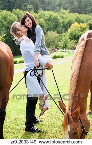 Caucasian couple in early twenties laughing and embracing in a pasture with horses, Winelands, Stellenbosch region, Cape Town, Western Cape, South Africa. View Large Photo Image Stock Photo - Caucasian couple in early twenties laughing and embracing in a pasture with horses, Winelands, Stellenbosch region, Cape Town, Western Cape, South Africa.. Fotosearch