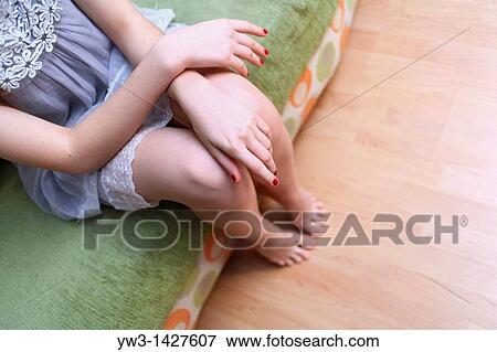 Stock Photo - Caucasian female bare legs indoors on sofa. Fotosearch
