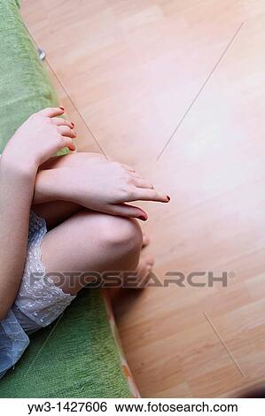Stock Photograph - Caucasian female bare legs indoors on sofa. Fotosearch