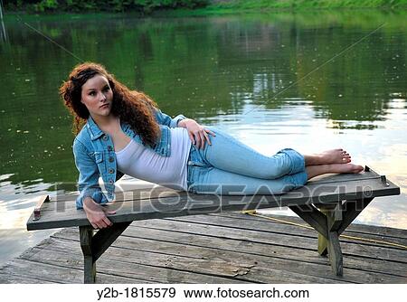 Caucasian female brown haired model eighteen year old lying on bench on wooden pier View Large Photo Image Stock Photo - Caucasian female brown haired model eighteen year old lying on bench on wooden pier. Fotosearch