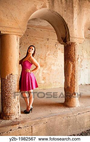 Stock Photo - Caucasian female model wearing bright pink dress standing by columns of automobile tunnel in urban Memphis Tennessee USA.. Fotosearch