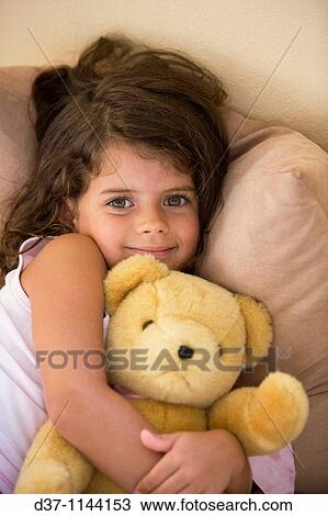 Stock Image - Caucasian girl hugging her teddy bear. Fotosearch