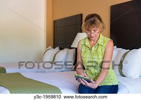 Stock Image - Caucasian woman, 45 years, using digital tablet device after arrival in a hotel room.. Fotosearch