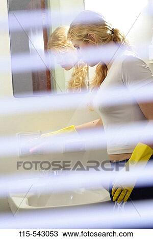 Caucasian woman in her 20's cleans the bathroom with blinds blurred in the foreground View Large Photo Image Stock Image - Caucasian woman in her 20's cleans the bathroom with blinds blurred in the foreground. Fotosearch