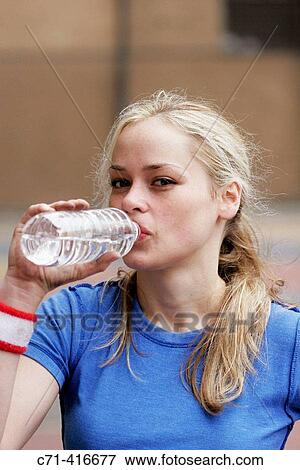 Stock Photo - Caucasian woman on basketball court drinking water. Fotosearch