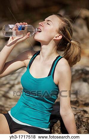 Caucasian young woman drinking water after exercise View Large Photo Image Stock Photo - Caucasian young woman drinking water after exercise. Fotosearch