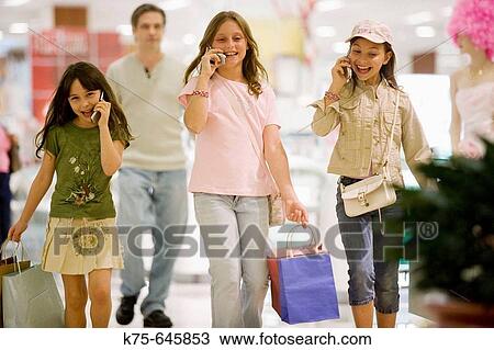 Stock Image - caucasians, hispanic, ages 9 and 10, cell phones, shopping, talking, laughing, happy, young consumers, dad as escort. Fotosearch