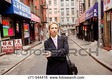 Stock Photograph - Caucassian businesswoman in middle of Chinatown street looking into camera. Fotosearch