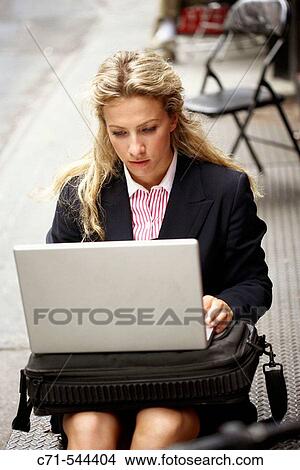 Caucassian businesswoman with laptop sitting on a stoop in a public street View Large Photo Image Picture - Caucassian businesswoman with laptop sitting on a stoop in a public street. Fotosearch