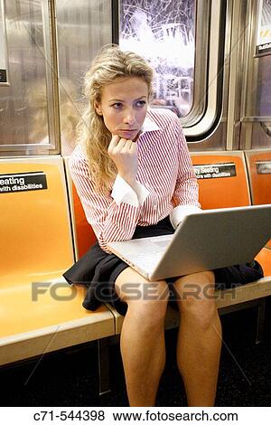 Stock Photo - Caucassian businesswoman with laptop sitting in subway car thinking. Fotosearch