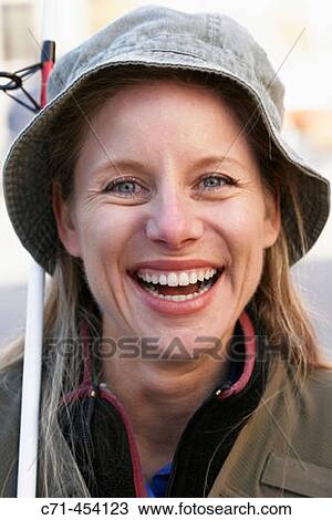 Stock Image - Caussian woman in fishing outfit and fishing pole smiling. Fotosearch