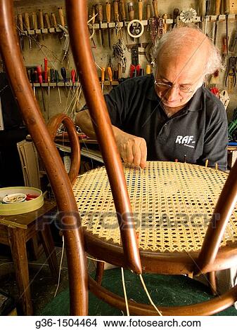 Picture - Chair caner repairs chair in shop in Rocca San Casciano, Emilia-Romagna, Italy. Fotosearch