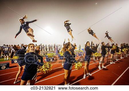 Cheerleaders entertain the spectators at a high school night football game in San Juan Capistrano, CA, hold initials of the school name. Note "flyers" on shoulders of other cheerleaders. View Large Photo Image Stock Image - Cheerleaders entertain the spectators at a high school night football game in San Juan Capistrano, CA, hold initials of the school name. Note "flyers" on shoulders of other cheerleaders.. Fotosearch