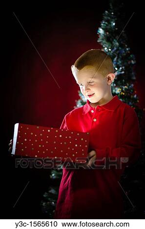 Stock Image - Child opening Christmas present. Fotosearch