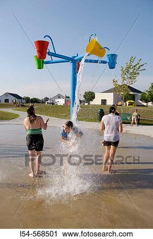Stock Image - Child playing at a public water park on a hot summer day. Fotosearch