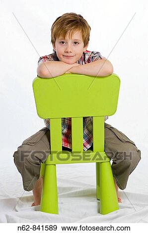 Stock Photo - child sitting astride on a green chair. Fotosearch