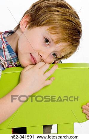 Stock Image - child sitting on a chair with his head resting on the seat back. Fotosearch