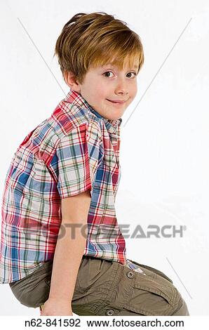 Stock Image - Child sitting on the back of a chair with a worried expression. Fotosearch