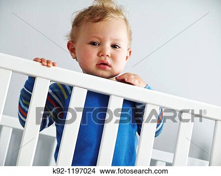 Child standing in a crib. View Large Photo Image Picture - Child standing in a crib.. Fotosearch