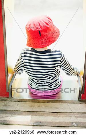 Childhood lifestyle moment. Little girl in read hat sitting at the top of a slide in a playground for children. View Large Photo Image Stock Photograph - Childhood lifestyle moment. Little girl in read hat sitting at the top of a slide in a playground for children.. Fotosearch