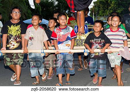 Stock Image - Children carrying Monster Figures at the Nyepi New Years Festival in Jimbaran on Bali, Indonesia.. Fotosearch