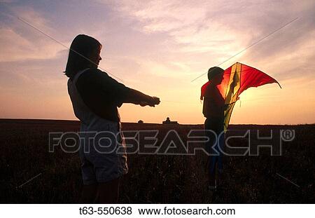 children flying a kite together outdoors at sunset View Large Photo Image Stock Photo - children flying a kite together outdoors at sunset. Fotosearch