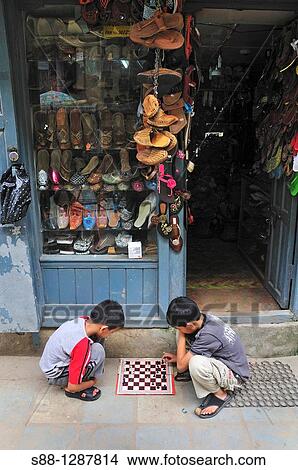 Picture - Children playing chess in front of the shop. Fotosearch