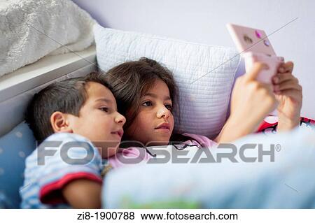 Stock Photo - Children playing computer games in bed. Fotosearch