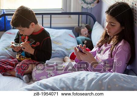 Children playing games on mobile devices in bed View Large Photo Image Stock Image - Children playing games on mobile devices in bed. Fotosearch