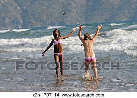 Picture - children playing in the waves of the Iztuzu beach, Dalyan, Turkey, Eurasia. Fotosearch
