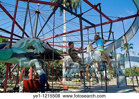 Children riding horses on a merry go round ride in Remedios Amusement Park, Cuba. View Large Photo Image Stock Photo - Children riding horses on a merry go round ride in Remedios Amusement Park, Cuba.. Fotosearch