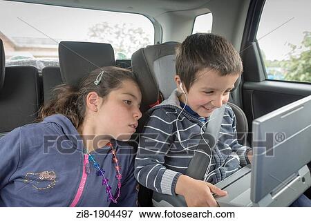 Stock Photo - Children watching a movie on the backseat of a car. Fotosearch