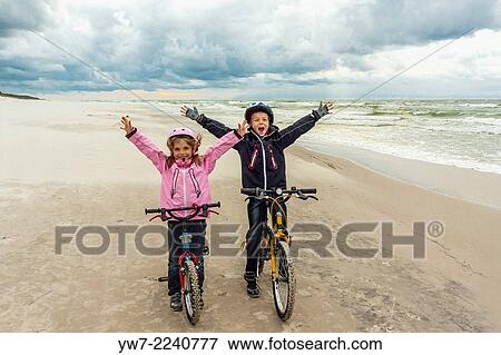 Stock Photo - Children with their bicycles on a beach in Bialogora, Poland.. Fotosearch