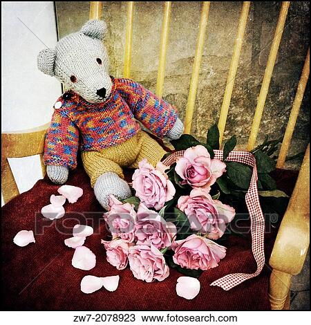 Stock Image - Childs hand crafted Teddy bear with bouquet of pink coloured Roses, textured image.. Fotosearch