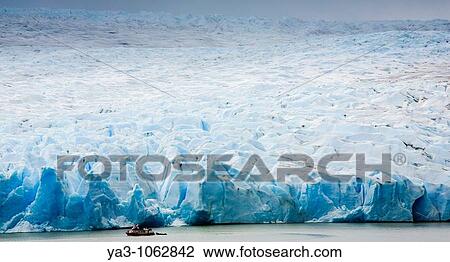 Stock Image - Chile, Southern Patagonia, Torres Del Paine National Park Tourist boat on the Lago Grey dwarfed by the sheer ice wall of the Grey Glacier and the Patagonian Ice Field. Fotosearch
