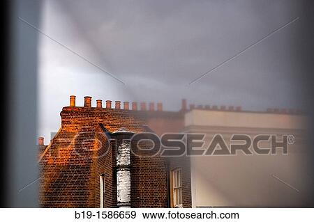 Stock Photo - Chimneys on the top of a London's building through the window and curtains. Fotosearch