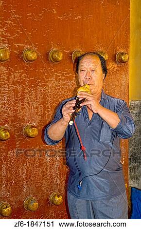 Stock Image - China Beijing Local man plays ancient flute for tourists in Beijing Forbidden City. Fotosearch