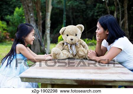 Stock Photo - China, Hong Kong, Mother and daughter (8-9) playing in garden. Fotosearch