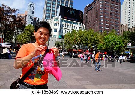Stock Photo - China, Shanghai, Huangpu District, Nanjing Road, People's Square, plaza, Asian, man, Park Hotel, Apple iPhone, taking picture,. Fotosearch