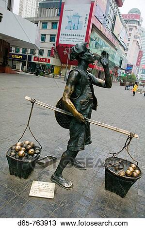 Stock Image - China. Yunnan Province. Kunming: Statue of Chinese laborer / shopping district. Fotosearch