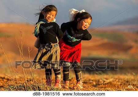 Stock Photograph - China, Yunnan Province, Kunming Municipality, Dongchuan District, Red soils, terrace cultivation, Gouditang village, girls playing.. Fotosearch