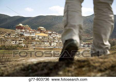 Stock Photograph - China Yunnan Shangri-La region Zhongdian, now called Shangri-La Chinese Man trekking and watching Ganden Sumsteling Gompa Songzanlin Si Buddhist Monastery. Fotosearch