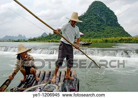 Chinese couple transporting tourists along the Yulong River on a bamboo raft, Yangshuo, Guangxi, China. View Large Photo Image Stock Photography - Chinese couple transporting tourists along the Yulong River on a bamboo raft, Yangshuo, Guangxi, China.. Fotosearch