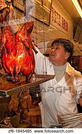Stock Photography - Chinese man arranging Peking Duck in window in Chinatown San Francisco California. Fotosearch