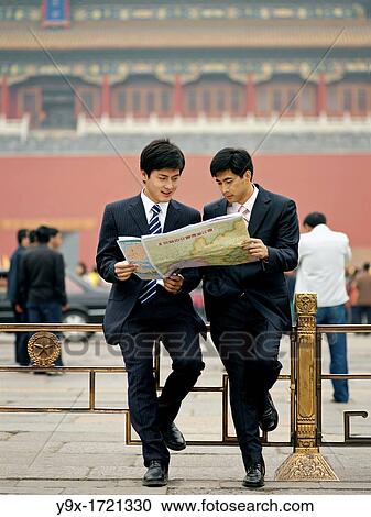 Stock Image - Chinese men looking at a map to help reorient or locate themselves. Fotosearch