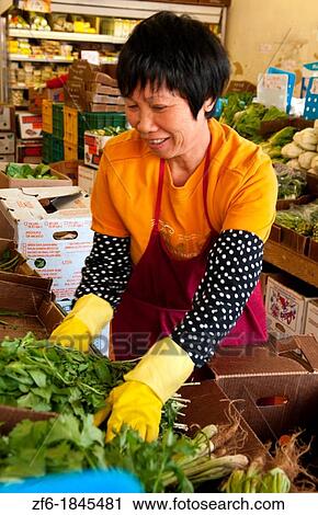 Stock Image - Chinese vendor woman arranging vegetables in Chinatown San Francisco California. Fotosearch