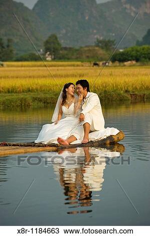 Chineses bride and groom pose for wedding photographies aboard a bamboo raft on the Yulong River, in the Yangshuo county, China. View Large Photo Image Stock Image - Chineses bride and groom pose for wedding photographies aboard a bamboo raft on the Yulong River, in the Yangshuo county, China.. Fotosearch