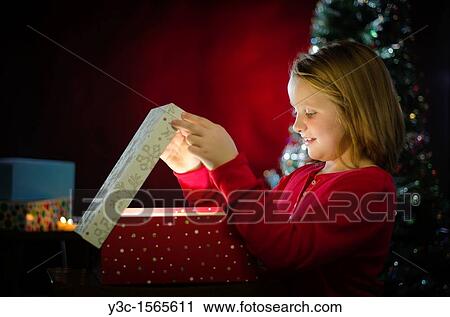 Stock Image - Christmas Eve - Happy child is opening a present. Fotosearch
