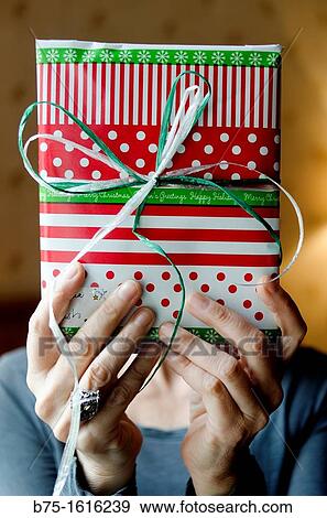 Stock Photo - Christmas Present in the hands covering the face. Fotosearch